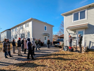 A group of individuals outside of a house during the ait-tightness testing demonstration