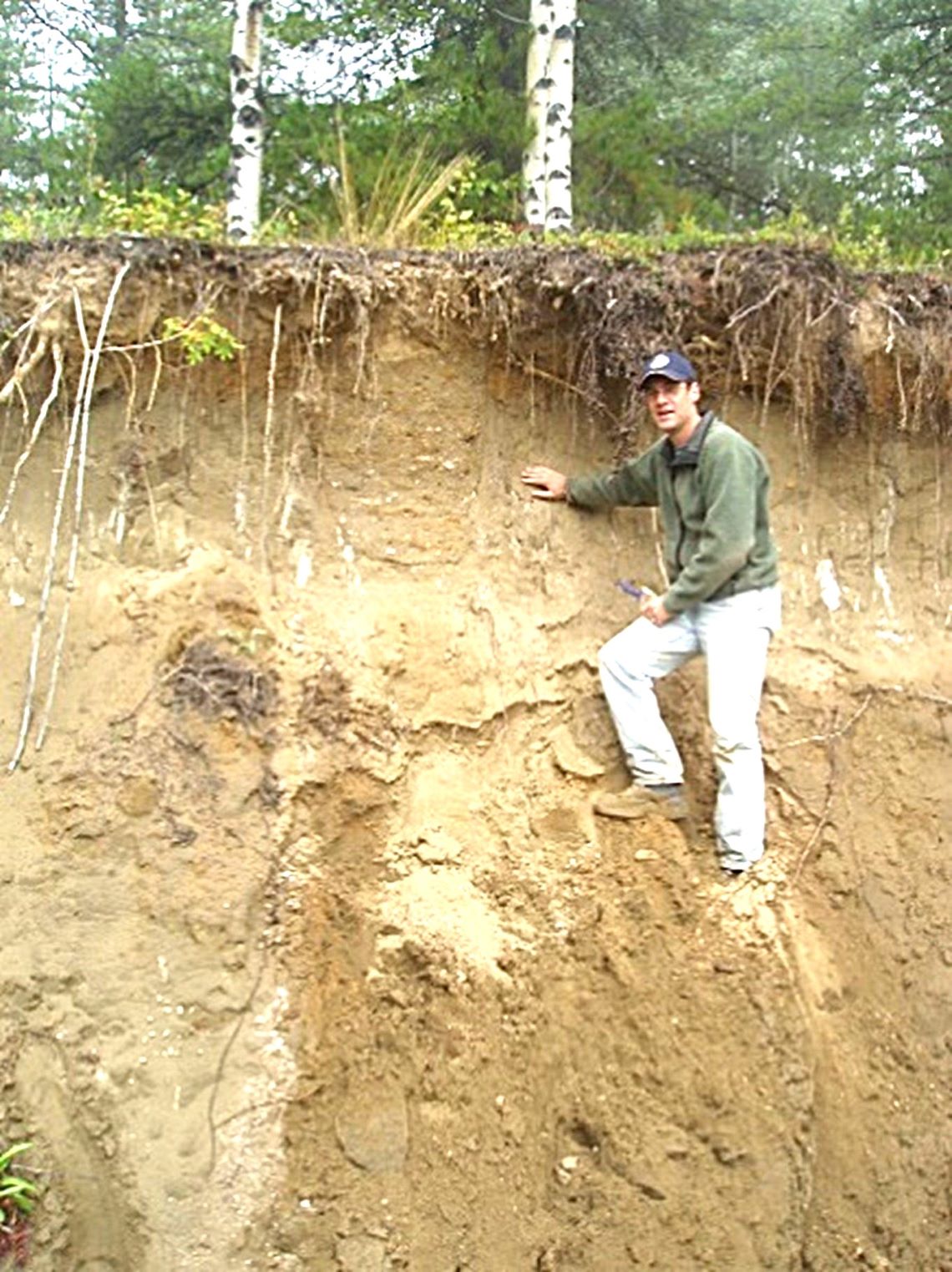 Man standing on the side of what appears to be a small cliff.