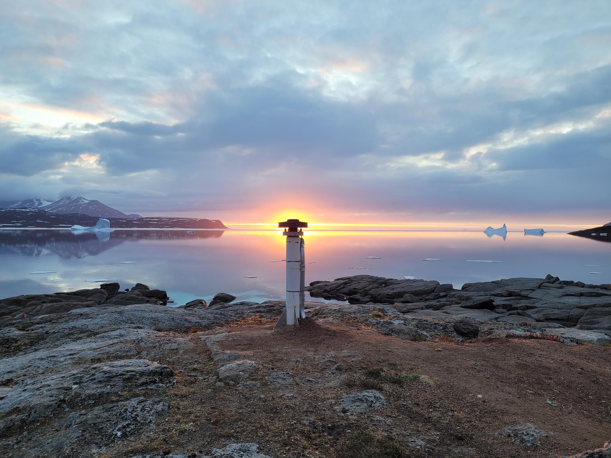 A coastal northern landscape featuring a fixed geodetic or navigational marker representative of CGS infrastructure used to support precise positioning.
