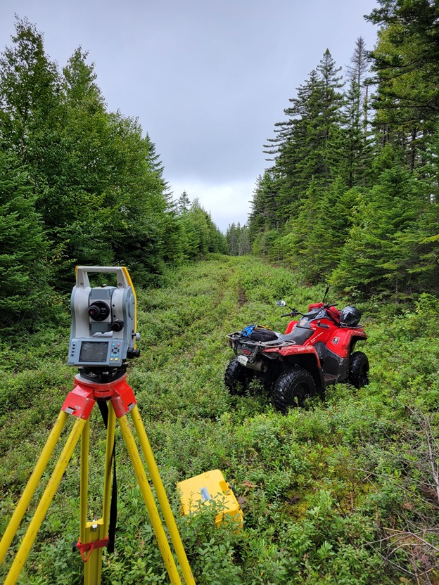 Surveying in a remote area along the international boundary displaying surveying equipment and an all-terrain vehicle.