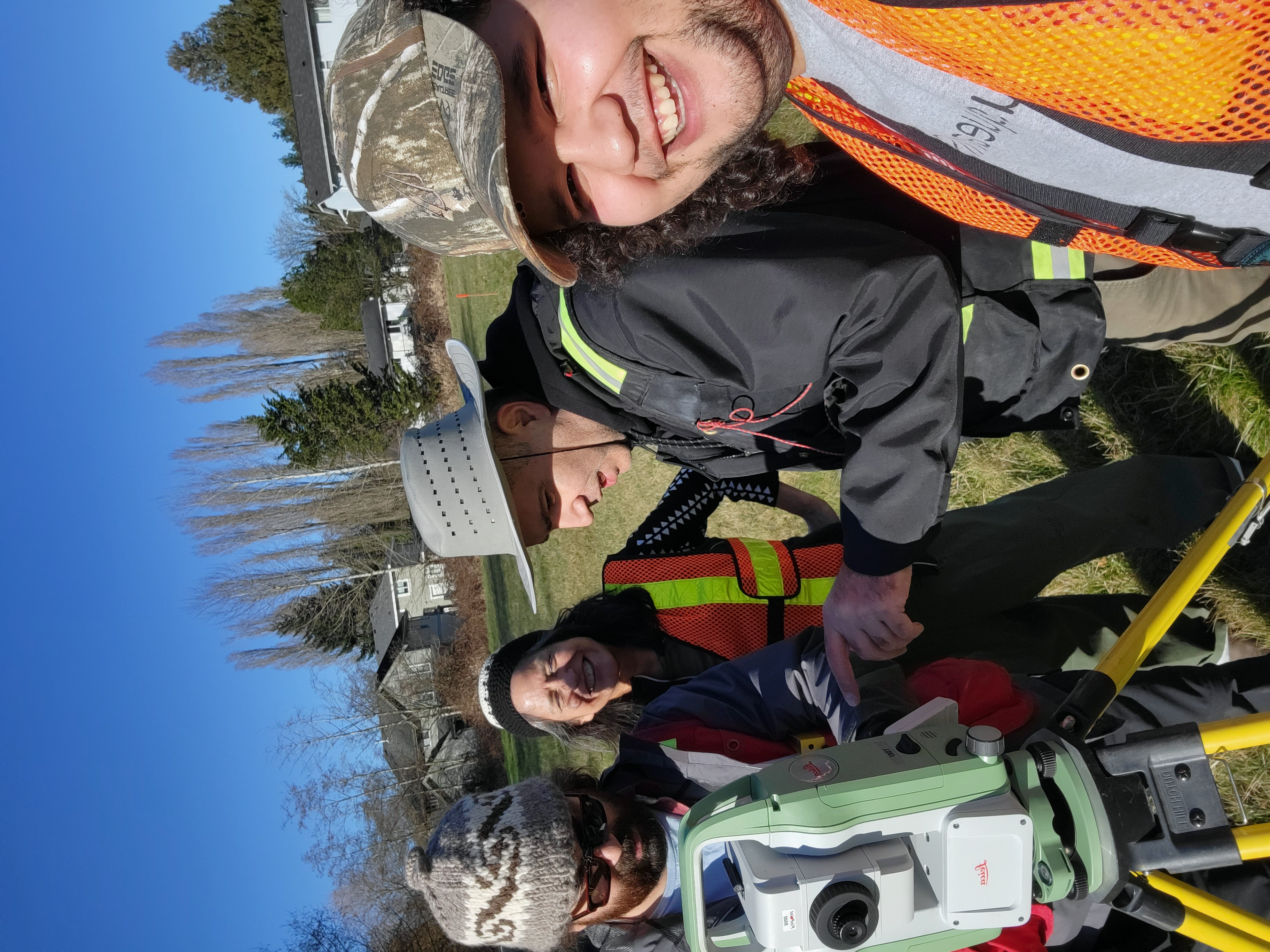 Four people with land surveying equipment at Musqueam.