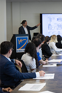 A presentation of blueprints to a table of people as part of the Kinetrics H3AT Tritium Loop project.