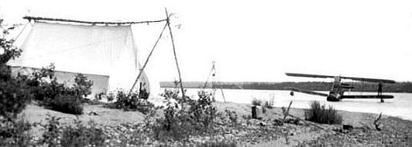 Plane on the water with tent on the side of the river